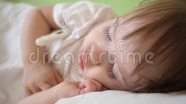 婴儿体温在医院病房用体温计测量.. 孩子睡在医院病房的白色床上。